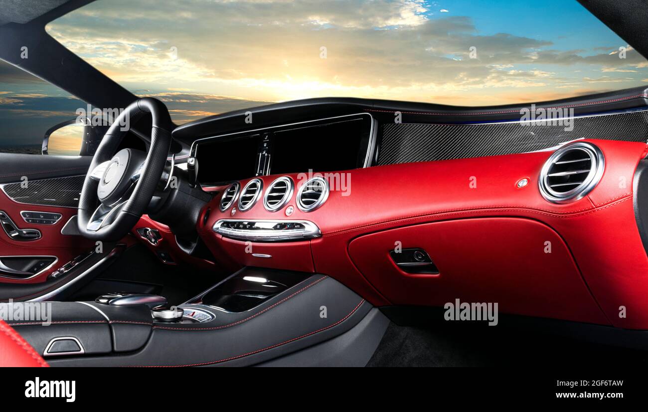 Red luxury modern car Interior. Steering wheel and dashboard. Detail of modern car interior. Automatic gear stick. Leather seats with stitching in exp Stock Photo