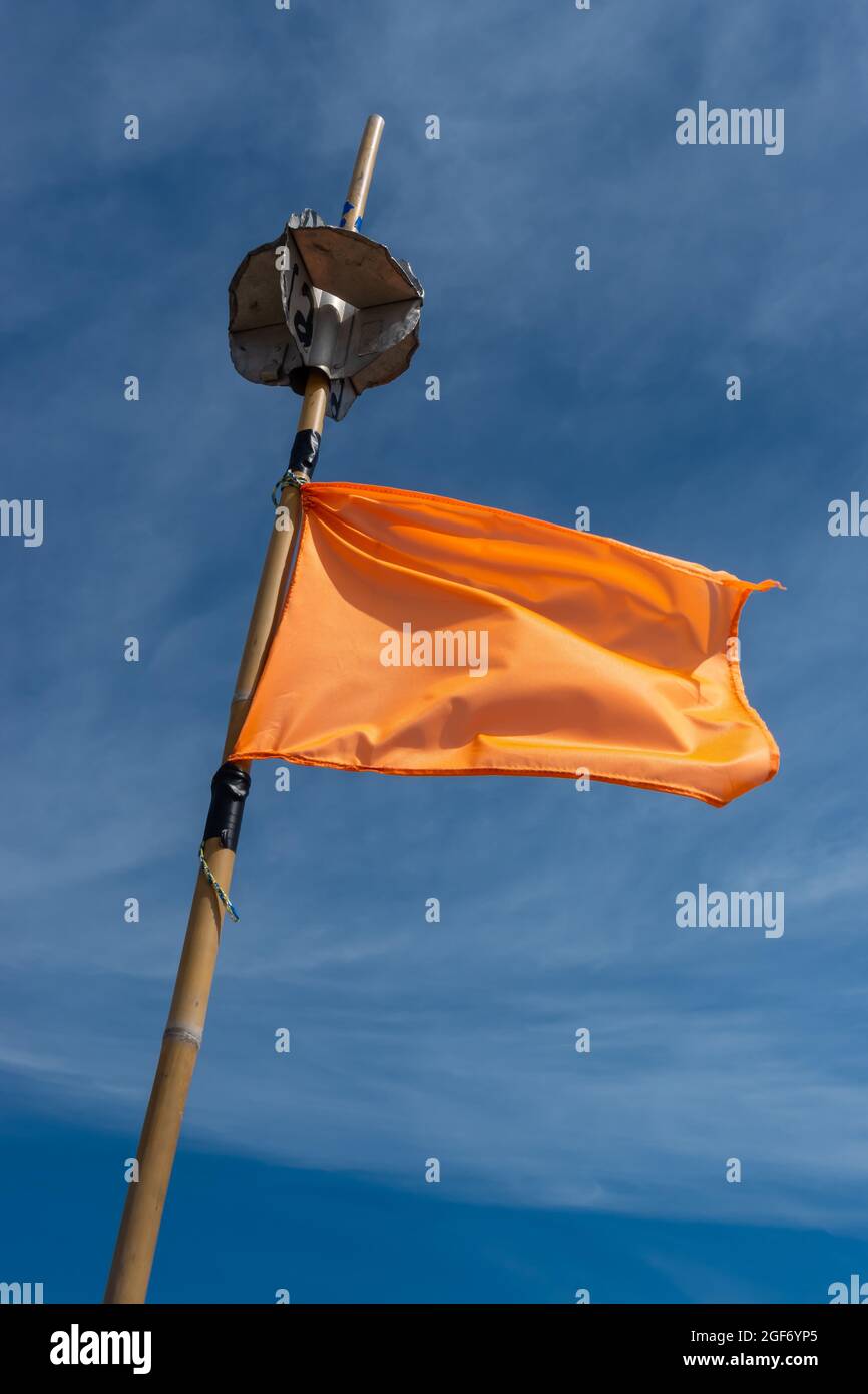 An orange fishing net marker flag waving in a high wind. The shot was