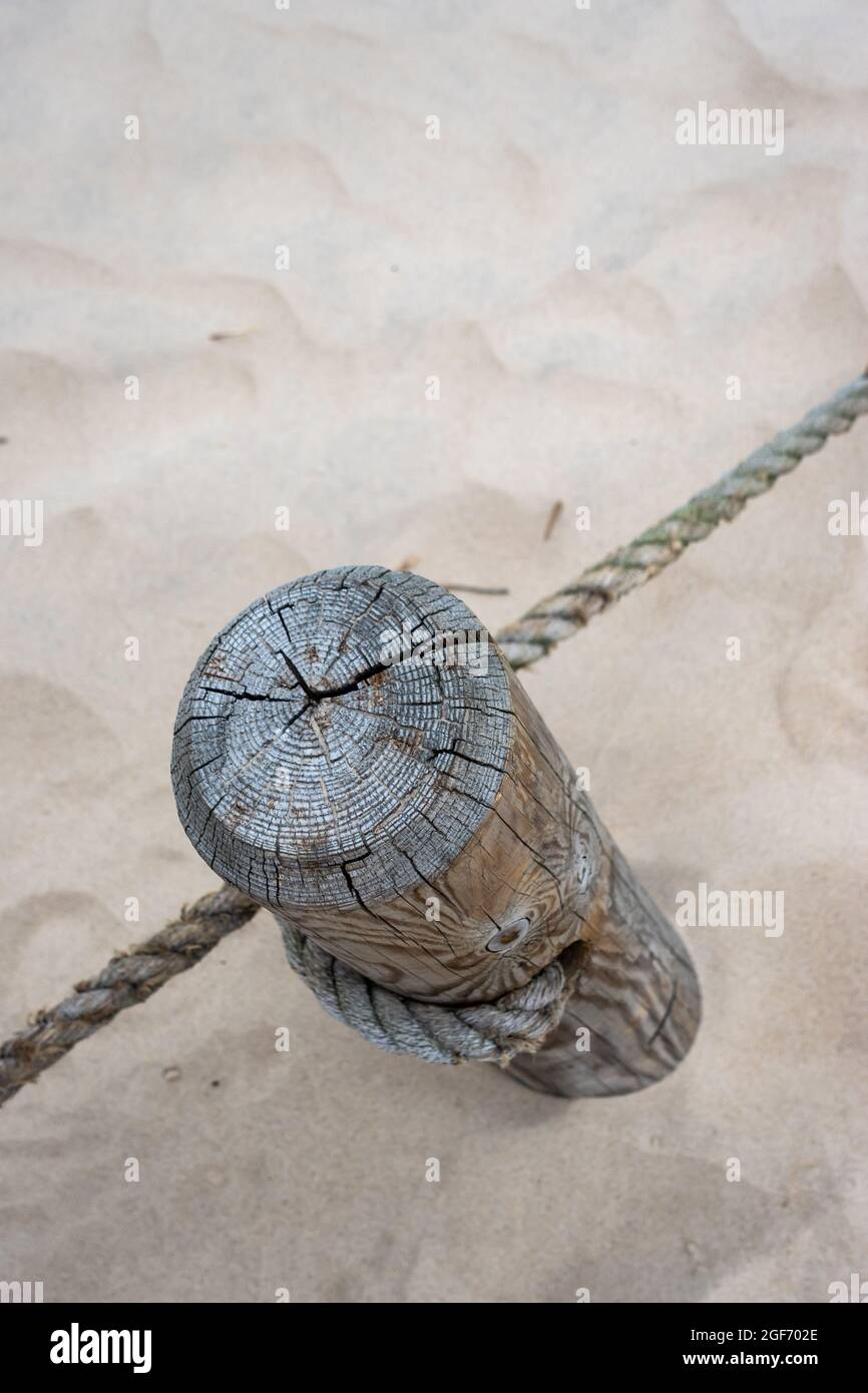 A wooden post with stretched ropes separating the hiking trail from the protected area. Photo taken in good lighting conditions on a cloudy day Stock Photo