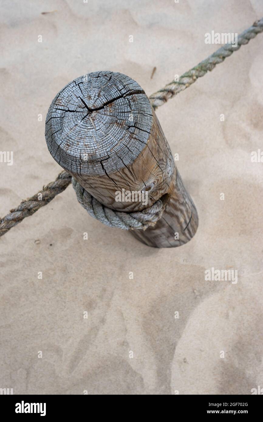 A wooden post with stretched ropes separating the hiking trail from the protected area. Photo taken in good lighting conditions on a cloudy day Stock Photo