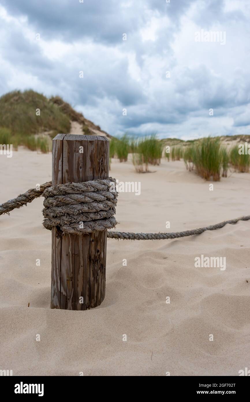 A wooden post with stretched ropes separating the hiking trail from the ...