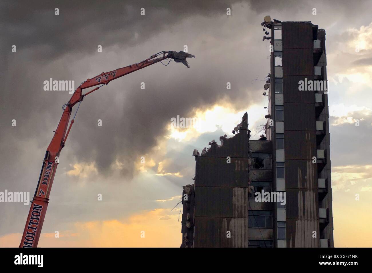Demolition of tower block in Woodford Essex, using crane with boom and nibbler. Sky has been digitally manipulated for dramatic effect Stock Photo