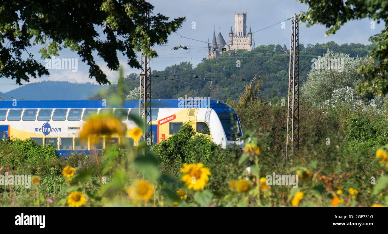 Nordstemmen, Germany. 24th Aug, 2021. A Metronom train travels along a  railway line in the district of Hildesheim within sight of Marienburg  Castle. The private railways in Lower Saxony are not affected