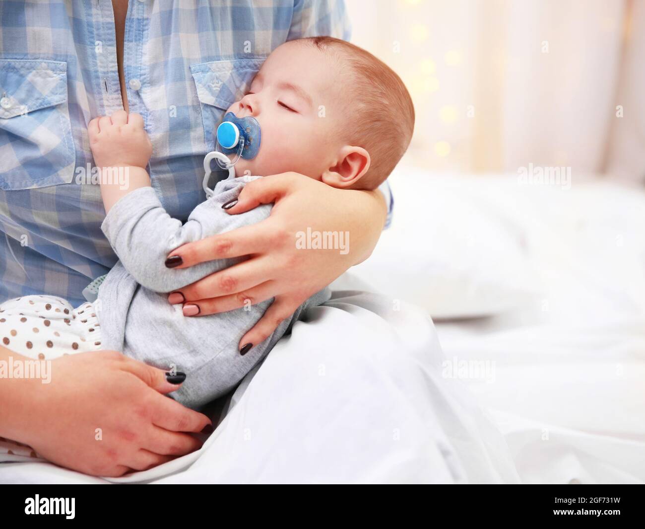 Loving baby with dummy sleeping in mother's hands, close up Stock Photo