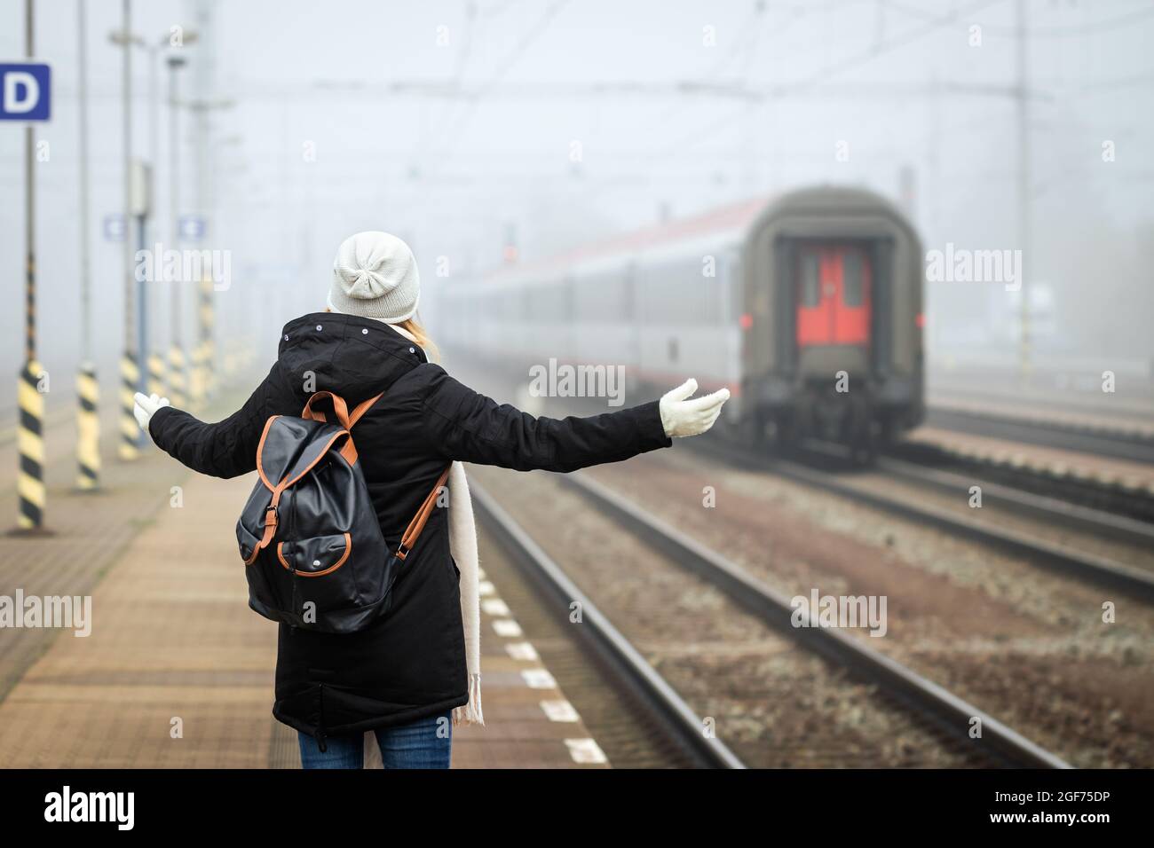 Woman traveler is at wrong railroad station platform and looking at leaving train.  Tourist with backpack travel by train Stock Photo