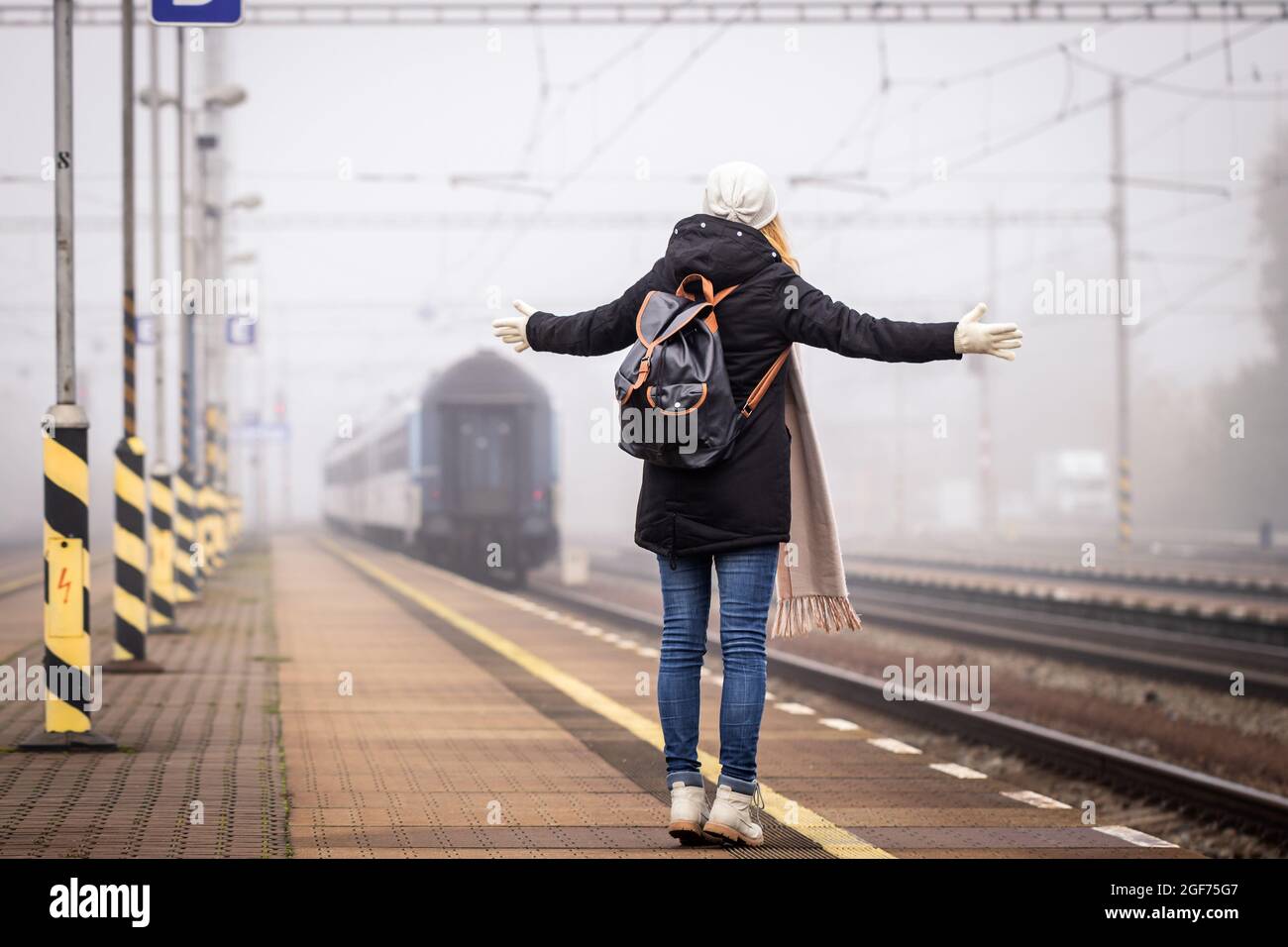 Disappointed traveler missed train. Woman tourist is looking at leaving train on railroad station Stock Photo