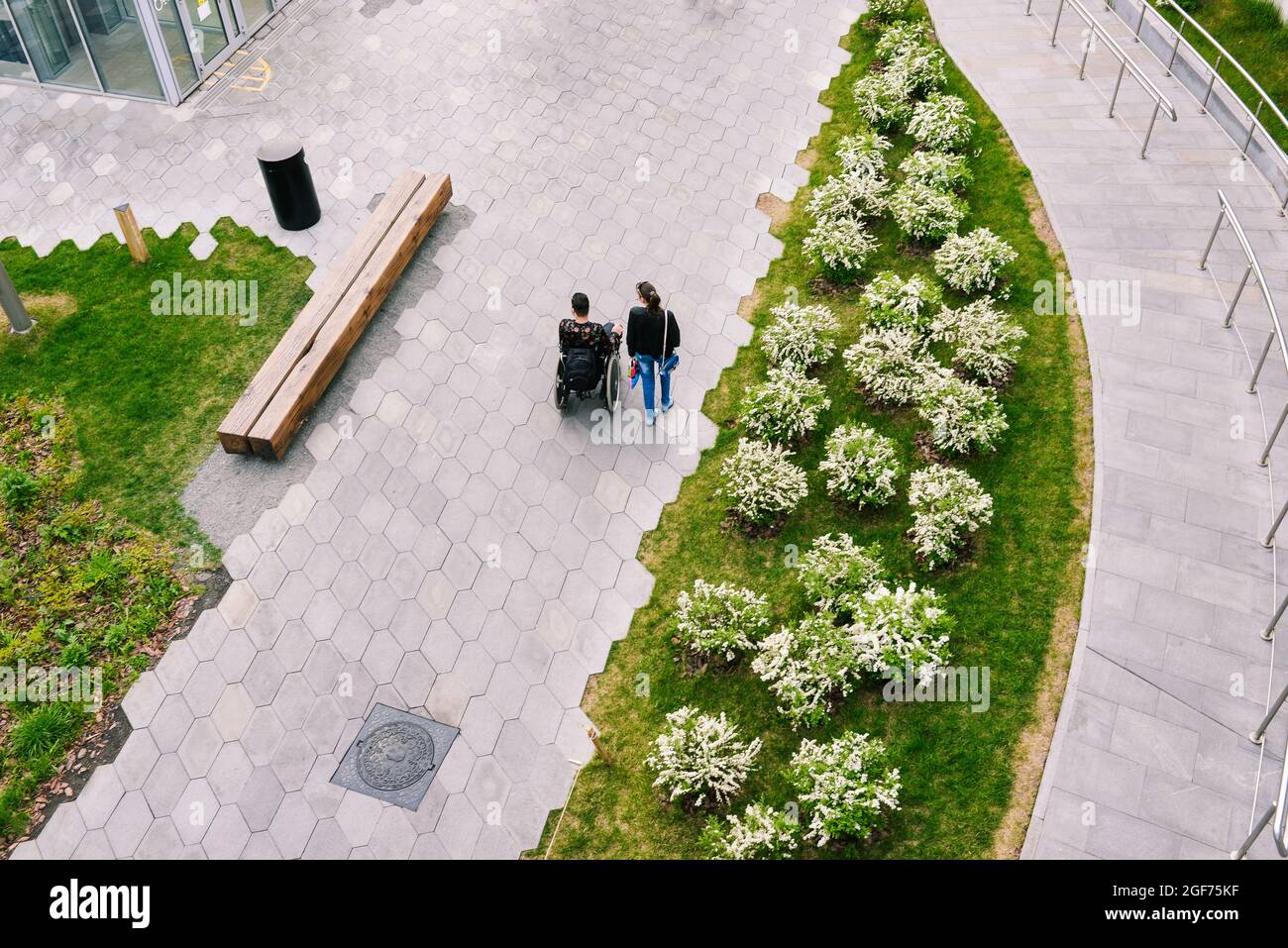 Man in a wheelchair is resting in a city park. A man and a woman are ...