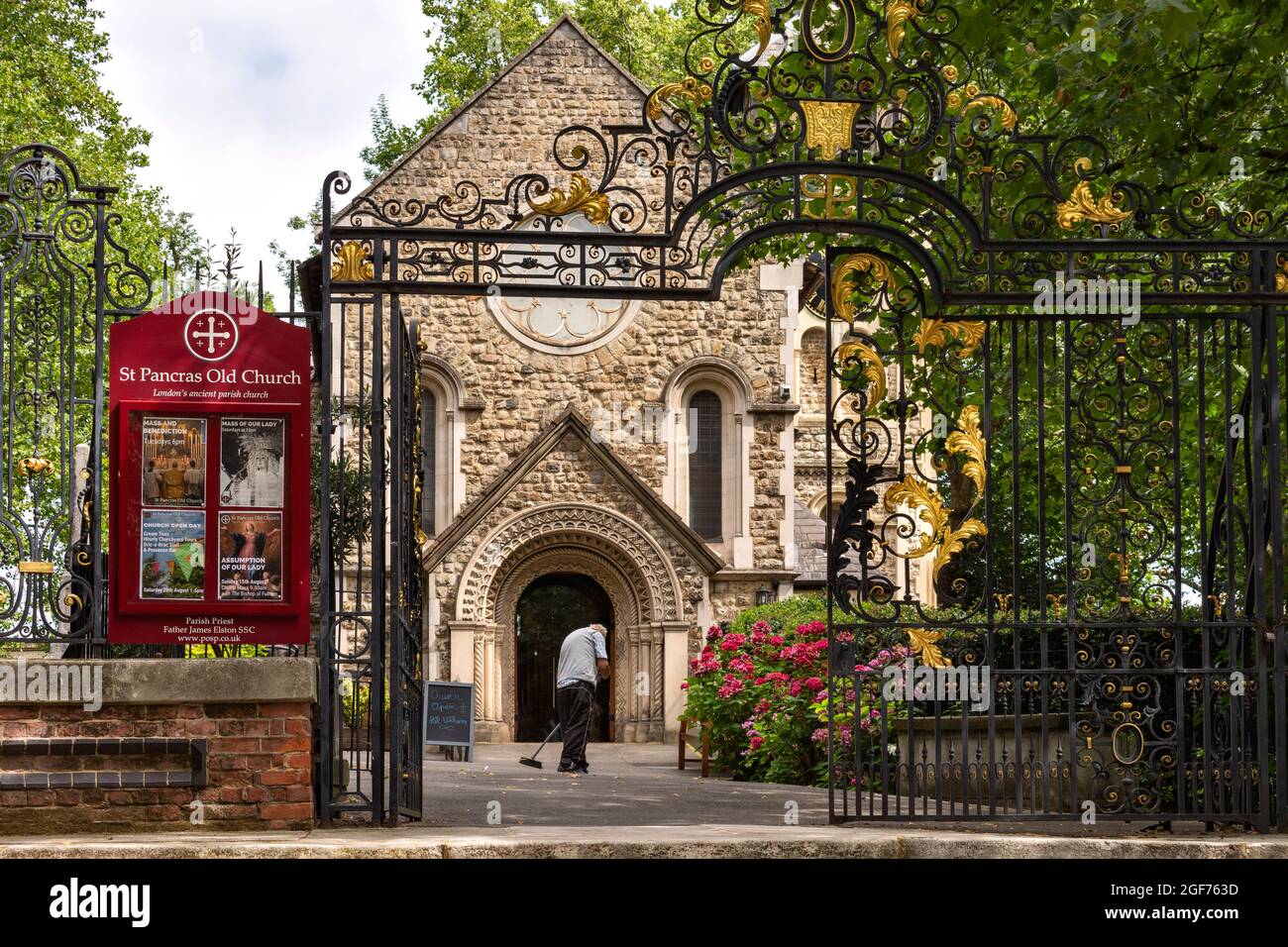 LONDON SOMERS TOWN SAINT PANCRAS OLD CHURCH SWEEPING LEAVES IN SUMMER Stock Photo