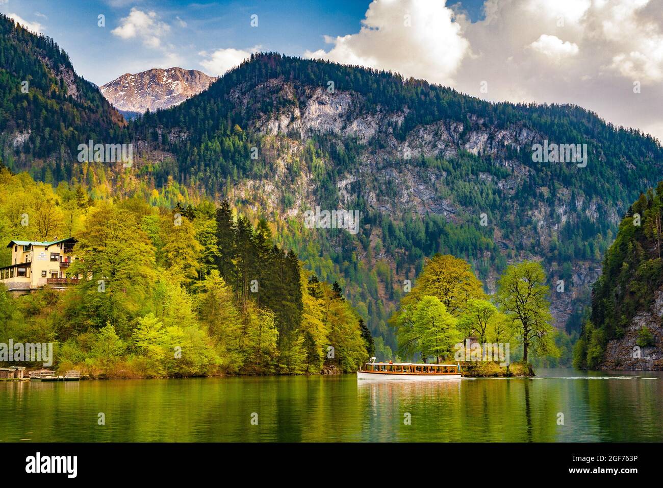 Beautiful tranquil landscape view of a white boat passing by the small Christlieger island on the famous Königssee lake. In the background are the... Stock Photo