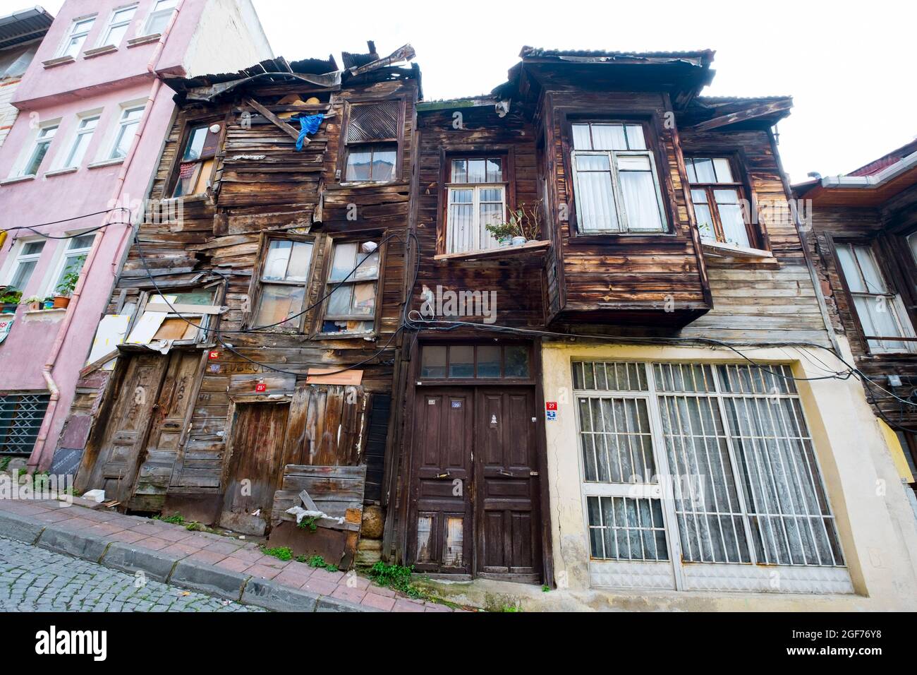 An example of a typical old, poor, worn, falling apart, unpainted, wood siding apartment building in a local neighborhood. In Istanbul, Turkey. Stock Photo