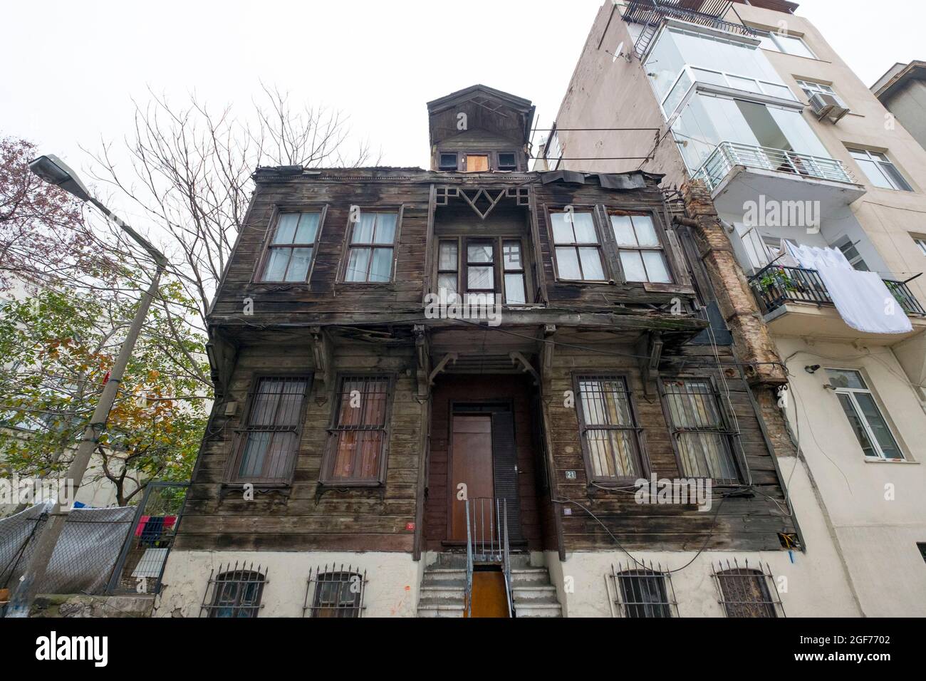 An example of a typical old, poor, worn, falling apart, unpainted, wood siding apartment building in a local neighborhood. In Istanbul, Turkey. Stock Photo