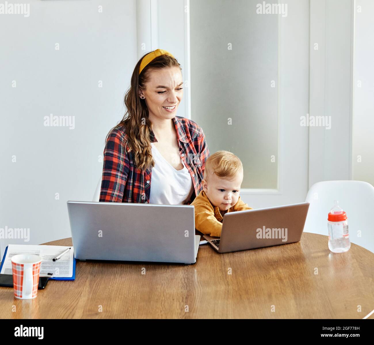 mother baby laptop computer child woman working business parent mom family Stock Photo