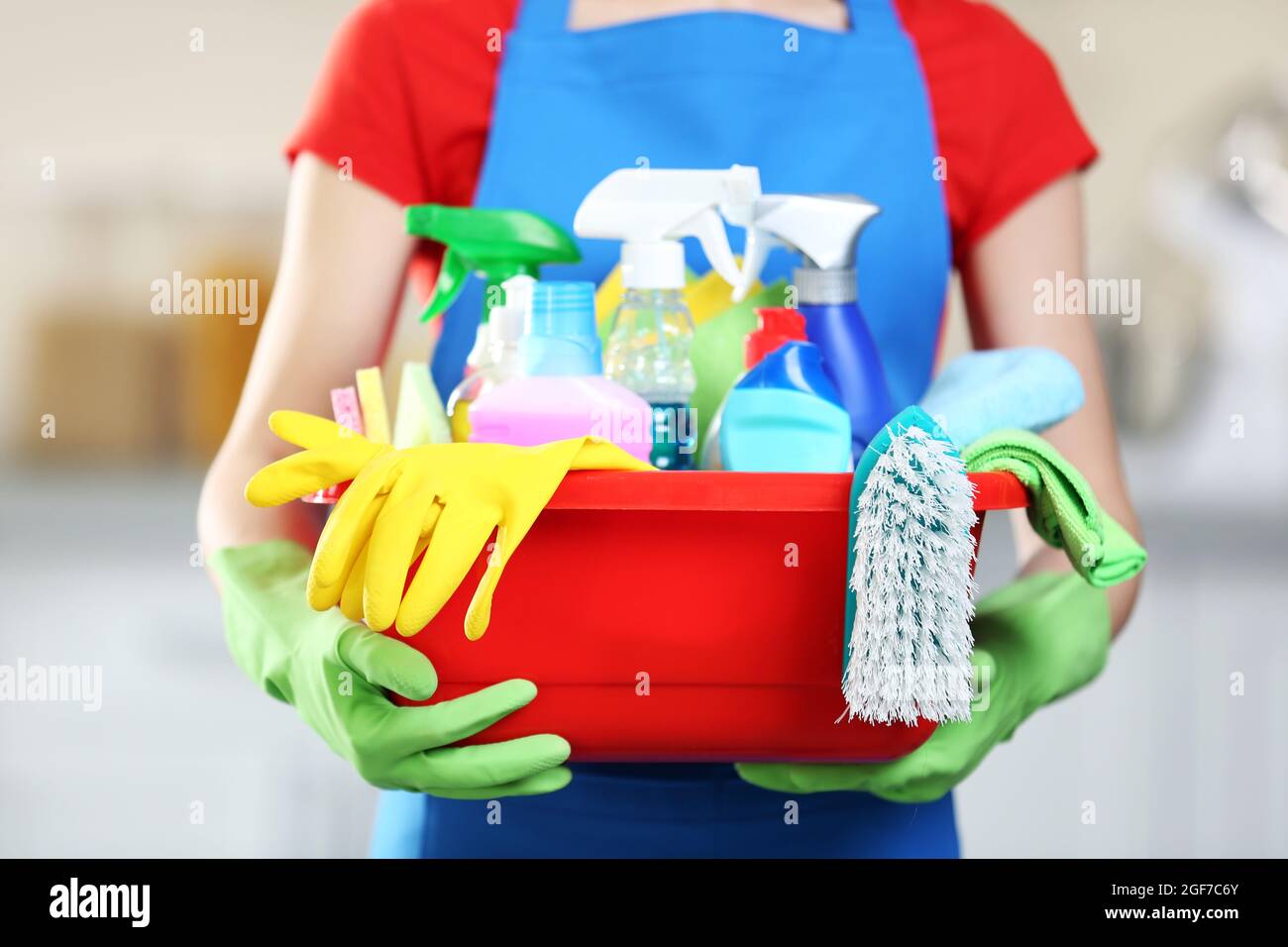 Cleaning concept. Young woman holds basin with washing fluids and rags