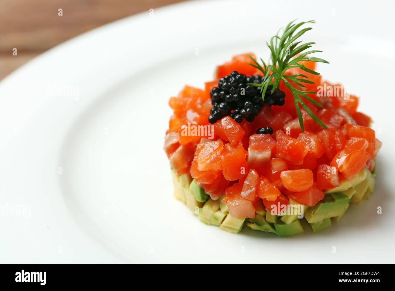 Delicious salmon tartare with black caviar on white plate Stock Photo
