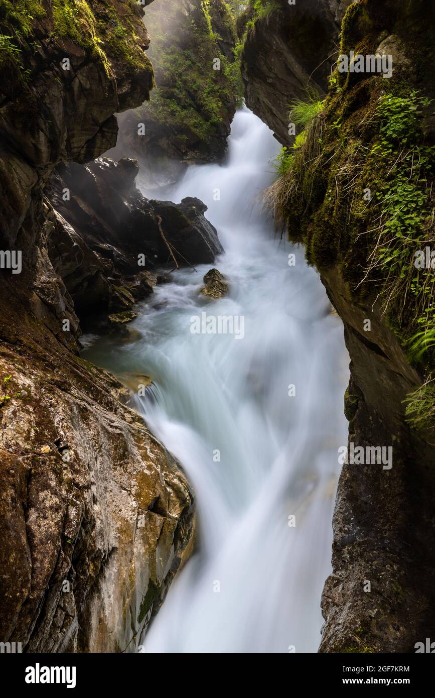 Close up of a mountain creek rushing into a gorge, surrounded by rocks and vegetation Stock Photo