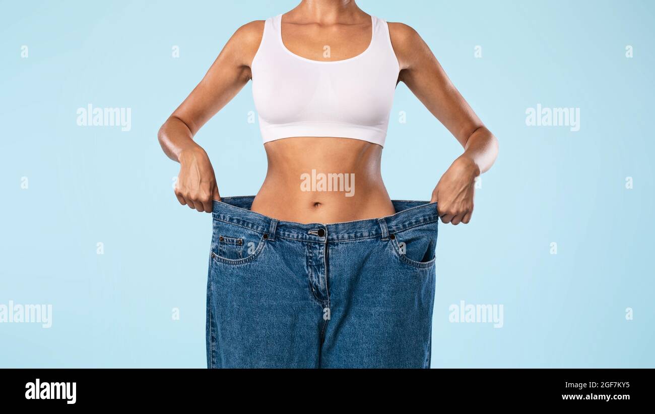 Closeup Of Skinny Woman Pulling Large Loose Jeans Stock Photo