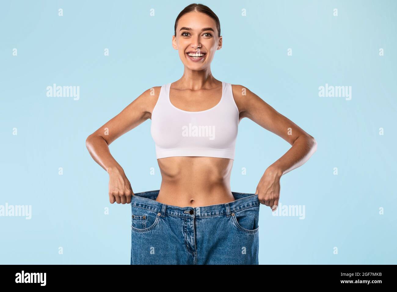 Woman Pulling Her Old Large Loose Jeans And Posing Stock Photo