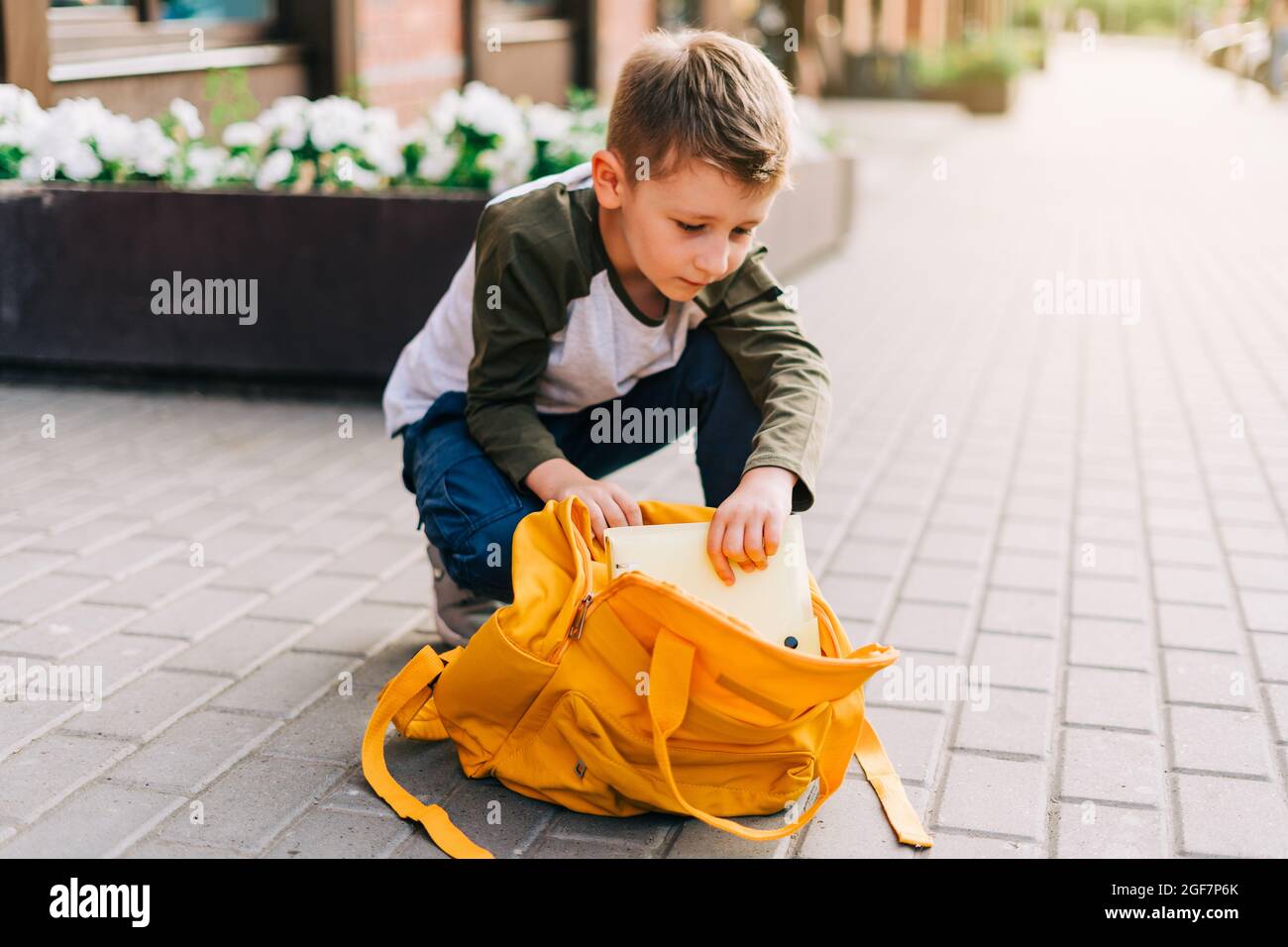 Back to school. Cute child packing backpack, holding notepad and training books going to school. Boy pupil with bag. Elementary school student going Stock Photo