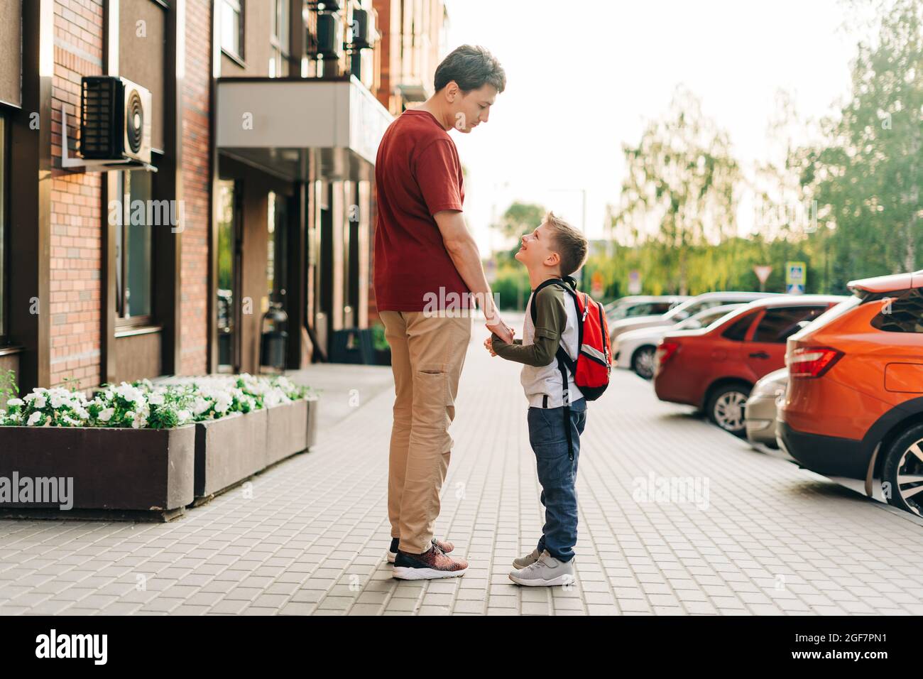 Happy father and kid son going to classes. Parent take child boy to school in first grade. Pupil of primary school go study with backpack outdoors in Stock Photo