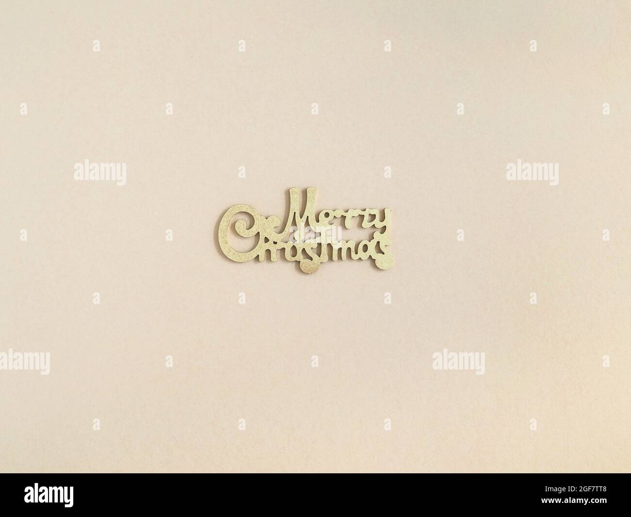 Merry Christmas gold greeting message on beige background. Top view. Minimal Beige Christmas greeting card. Stock Photo