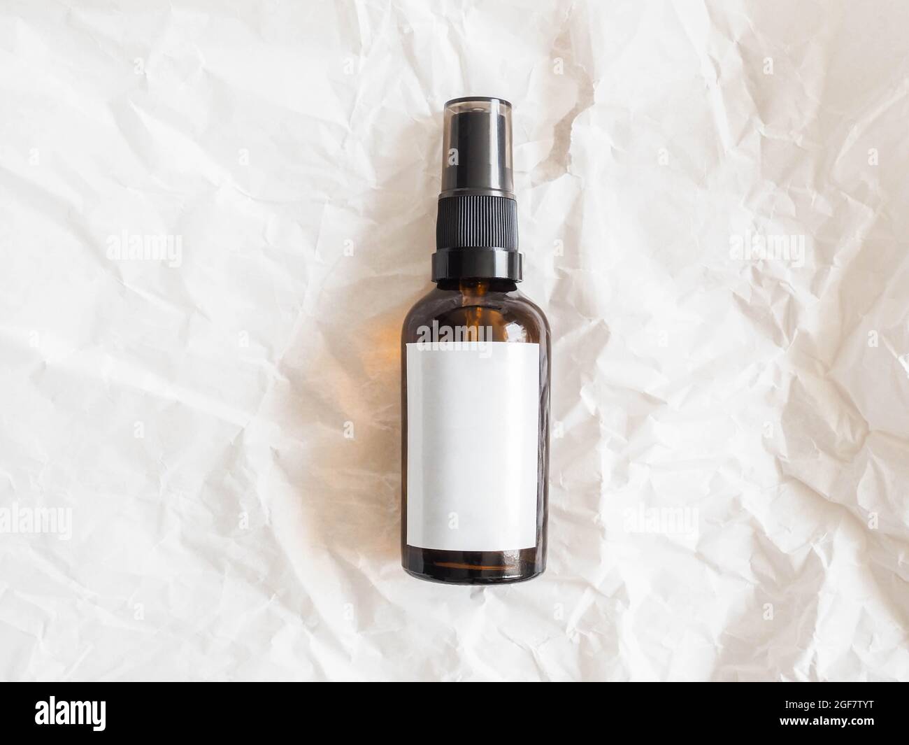 Mockup for care cosmetic product - amber bottle with white labels on crumpled white paper background. Top view. Copy space Stock Photo
