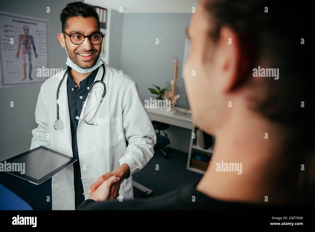 Mixed race male nurse chatting to patient in clinic Stock Photo