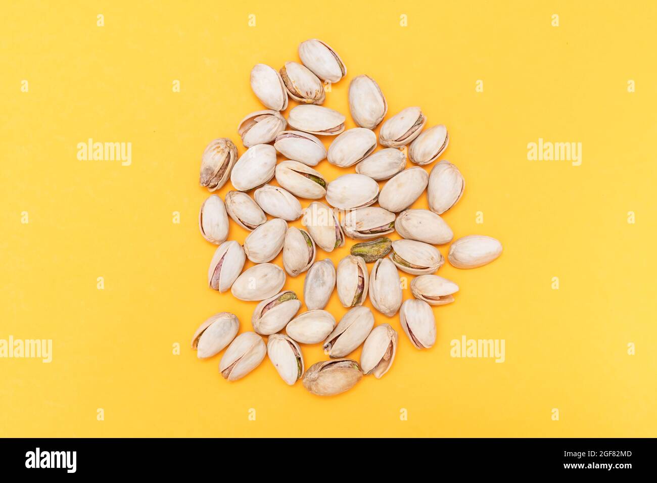 pile of pistachios on orange background. Nuts source of fiber. concept
