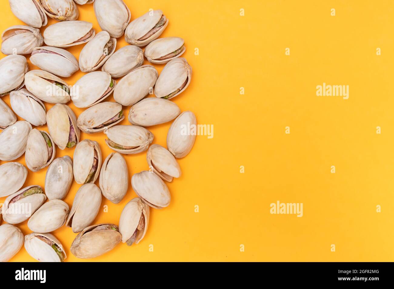 pile of pistachios on orange background. Nuts source of fiber. concept