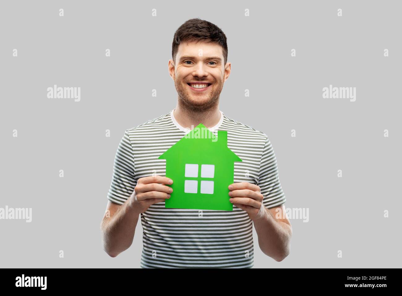 smiling young man holding green house icon Stock Photo
