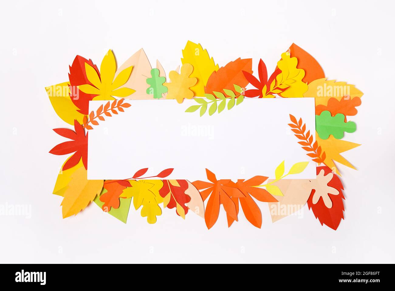 frame composed of colorful autumn paper leaves over white background ...