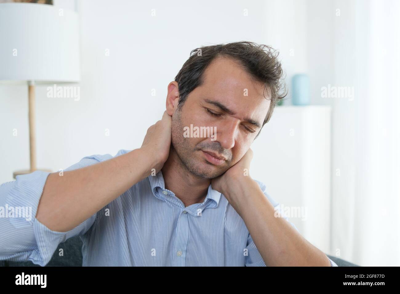 Man suffering neck pain from bad posture at home Stock Photo Alamy