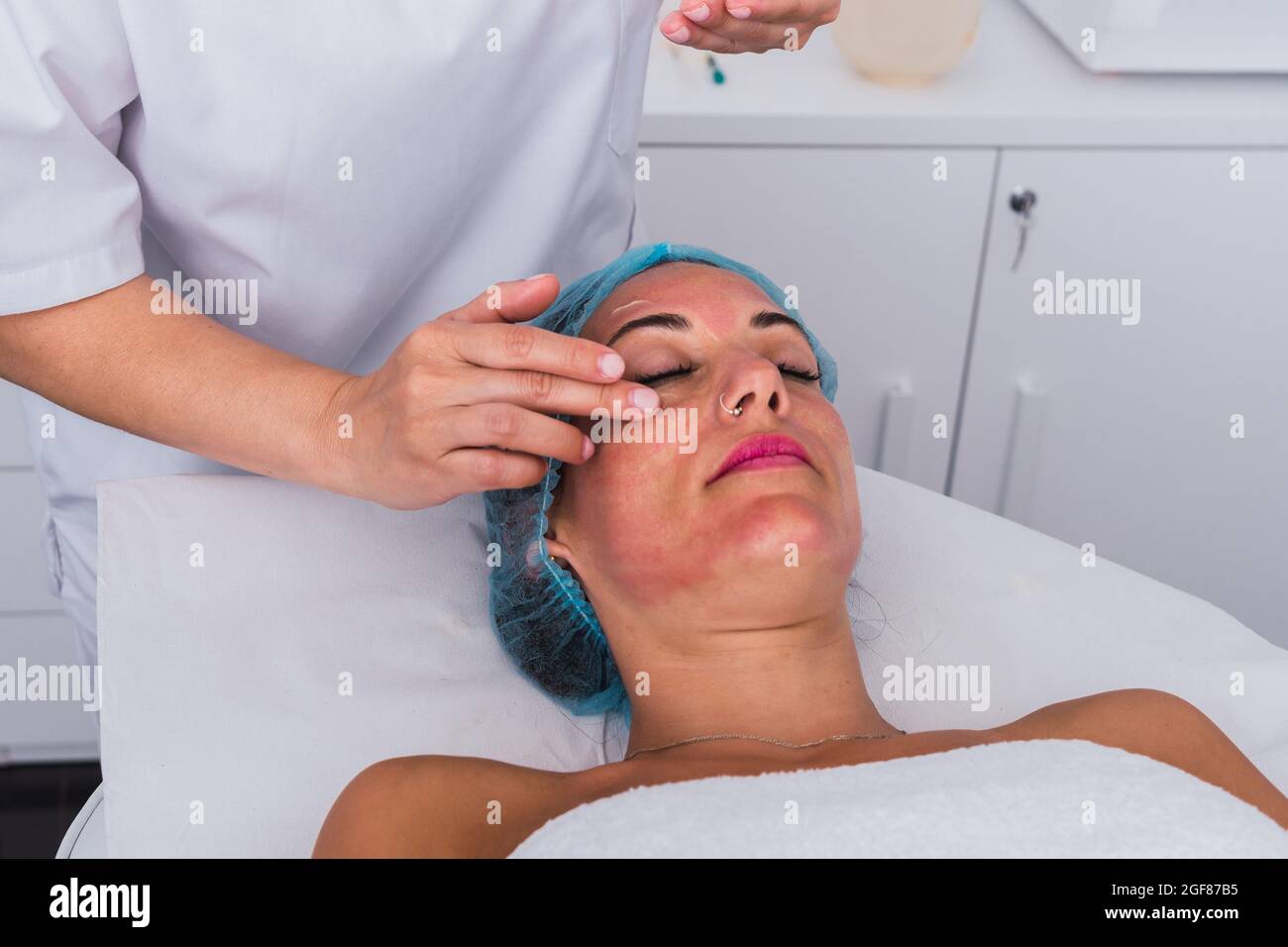 Cosmetologist applying facial massage cream to face of a woman in the beauty spa Stock Photo
