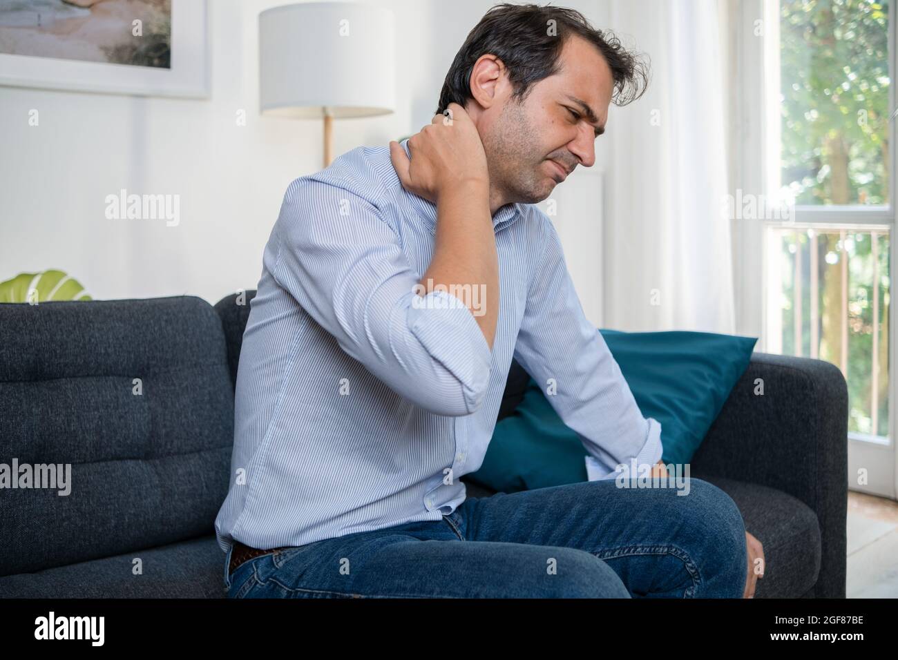 Man suffering neck pain from bad posture at home Stock Photo Alamy