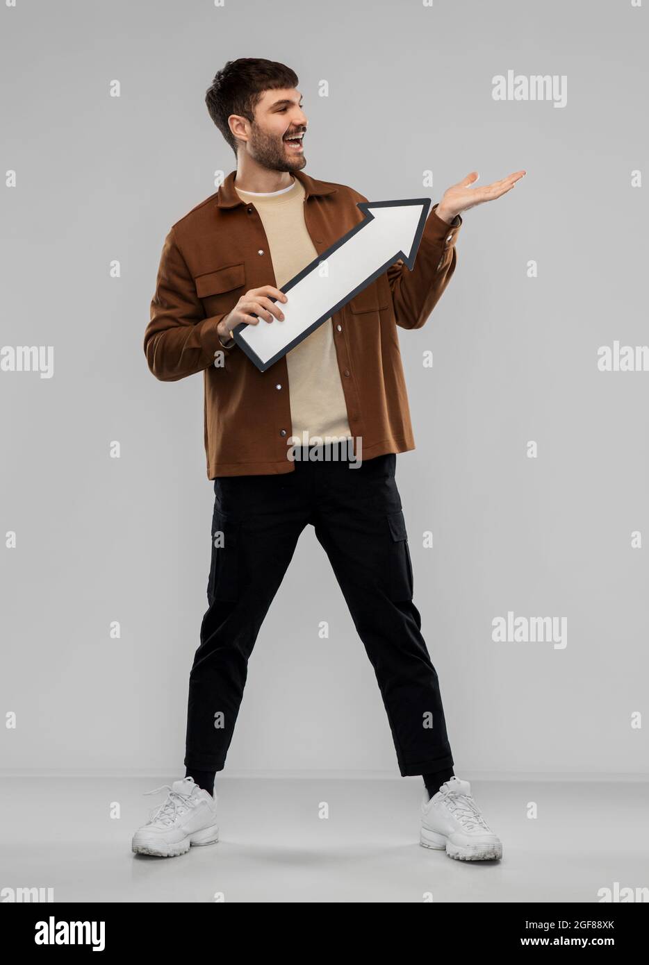 smiling young man holding big white arrow Stock Photo