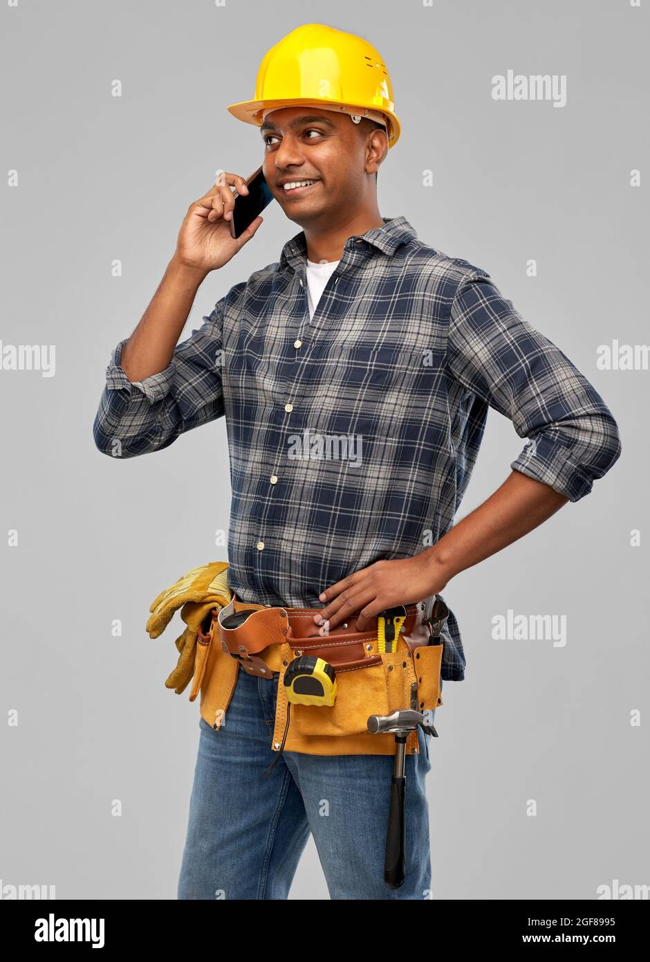 indian builder in helmet calling on smartphone Stock Photo