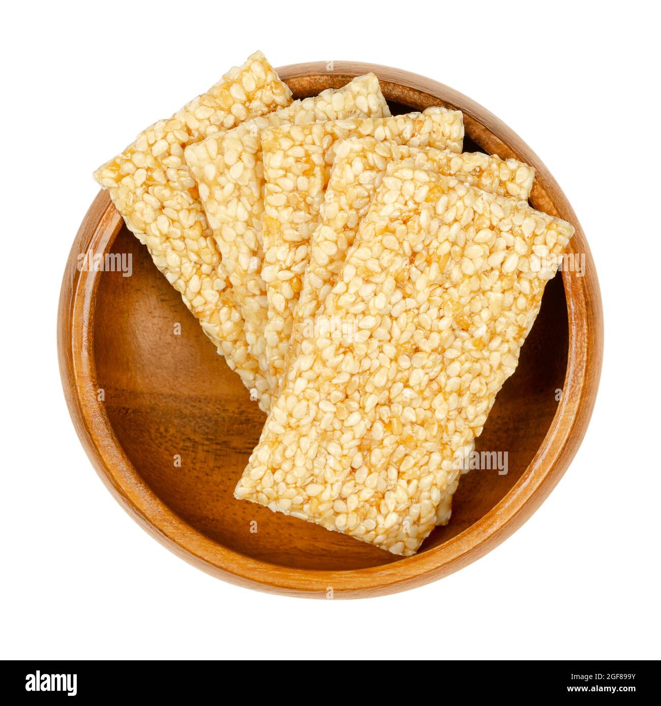Sesame seed candy bars, in a wooden bowl. Sesame brittle or crunch, a confection of sesame seeds and honey pressed into flat bars, a popular snack. Stock Photo