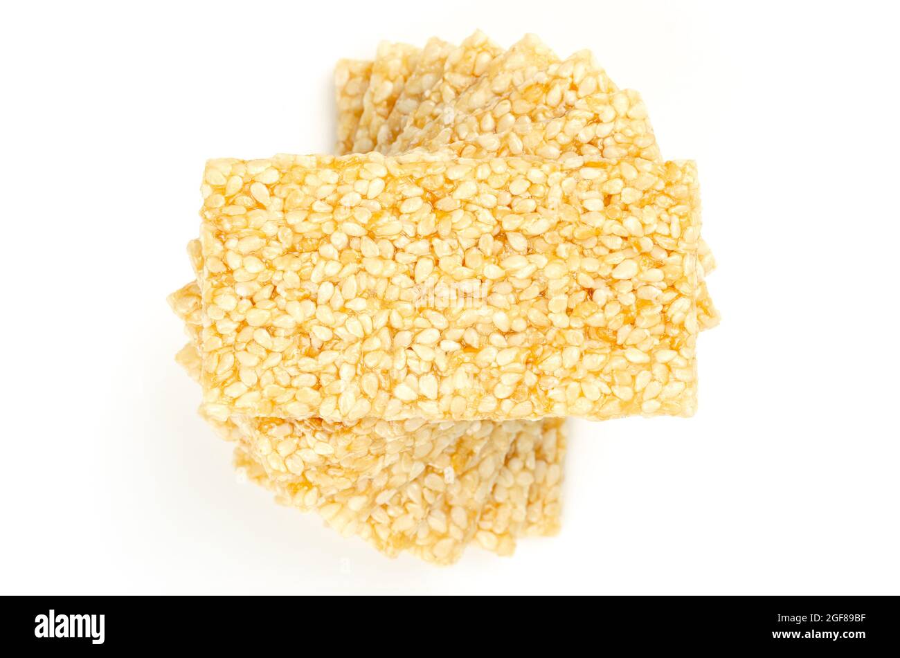 Pile of sesame brittle bars, from above, on white background. Sesame seed candy bars or also crunch, a confection of sesame seeds and honey. Stock Photo
