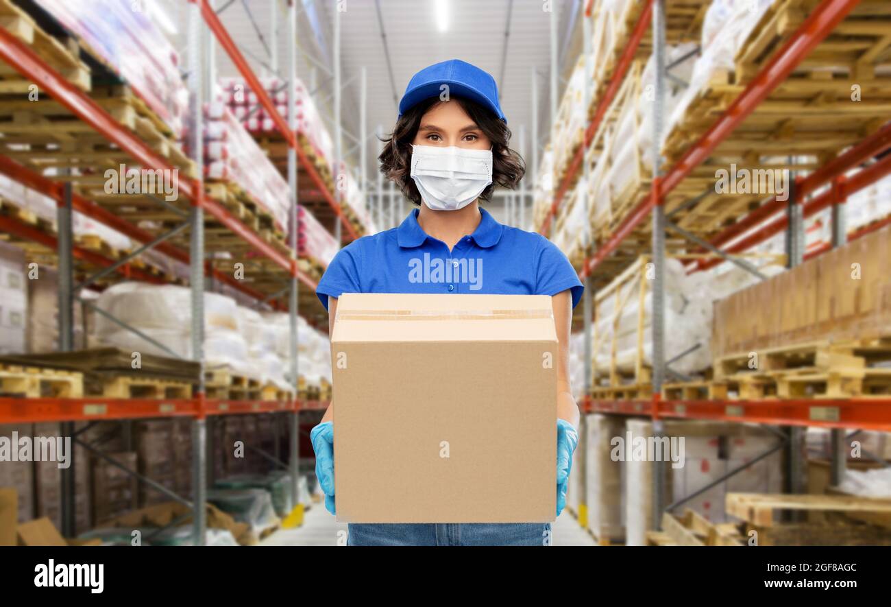 delivery woman in mask with box at warehouse Stock Photo - Alamy