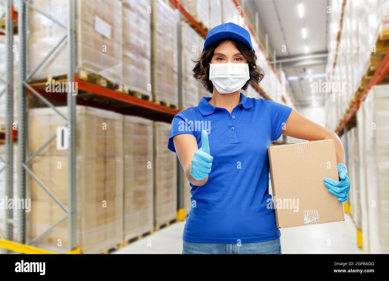 delivery woman in mask with box at warehouse Stock Photo - Alamy