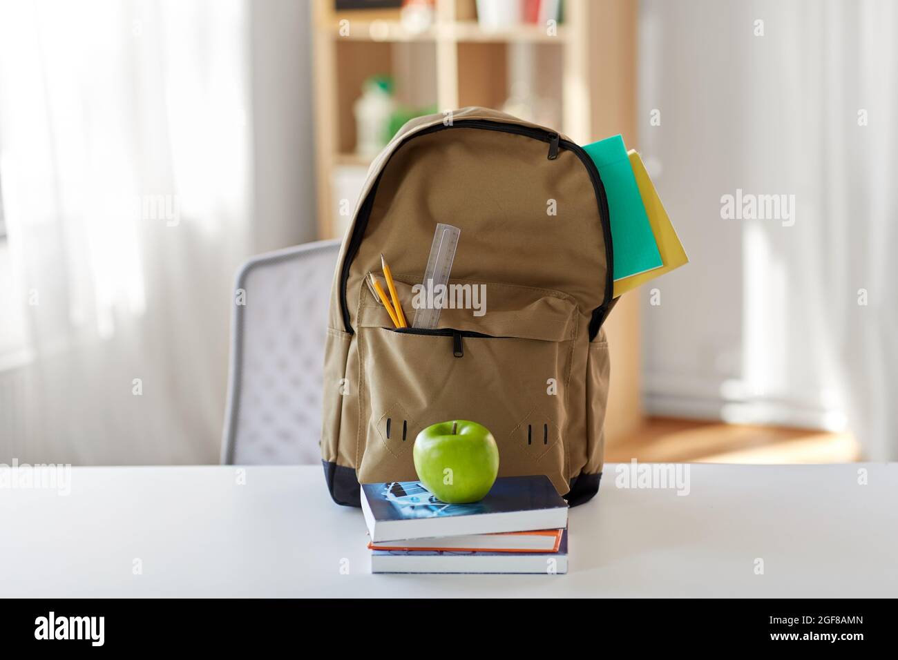 school backpack with books and apple on table Stock Photo