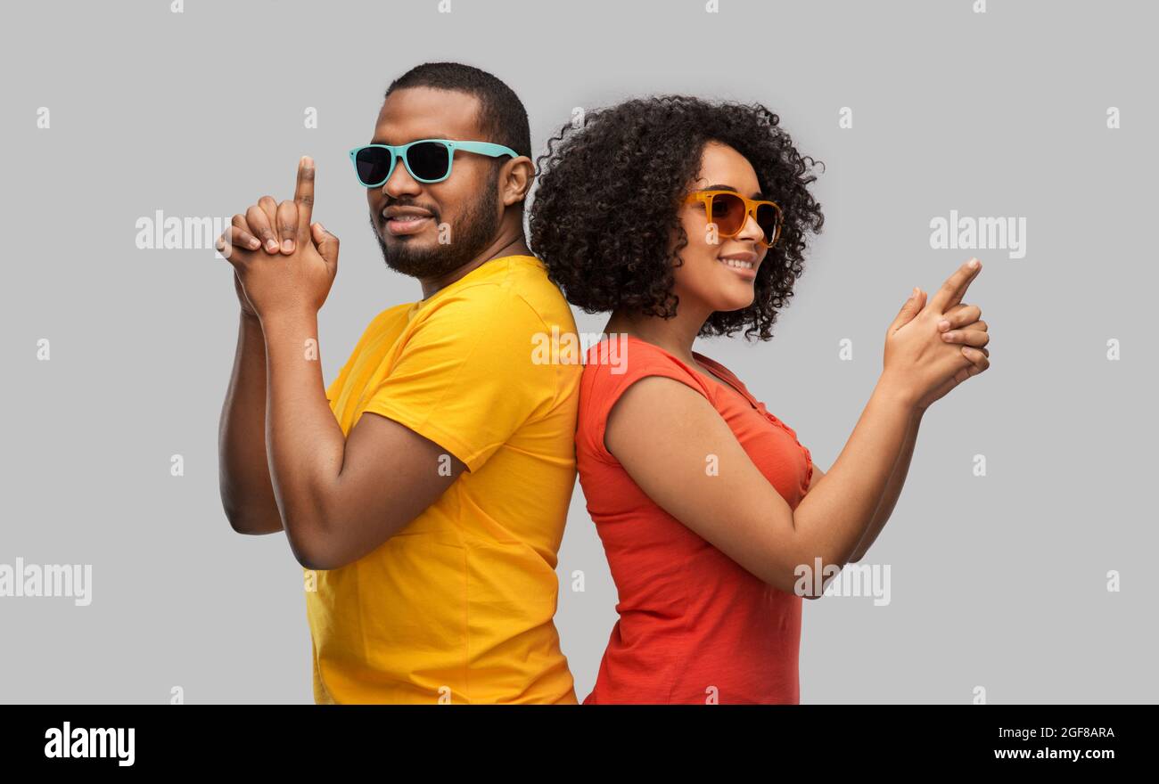 african couple in sunglasses making gun gesture Stock Photo