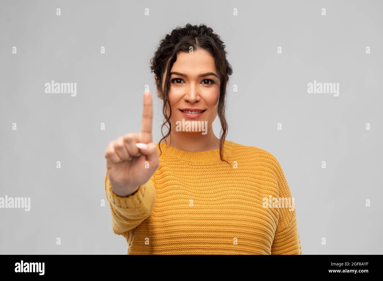 happy woman in pullover showing one finger Stock Photo