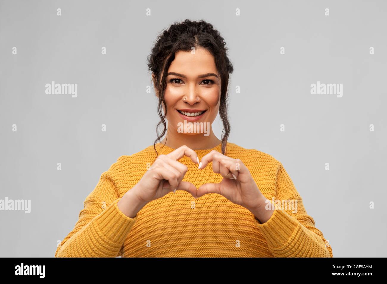 smiling young woman making hand heart gesture Stock Photo