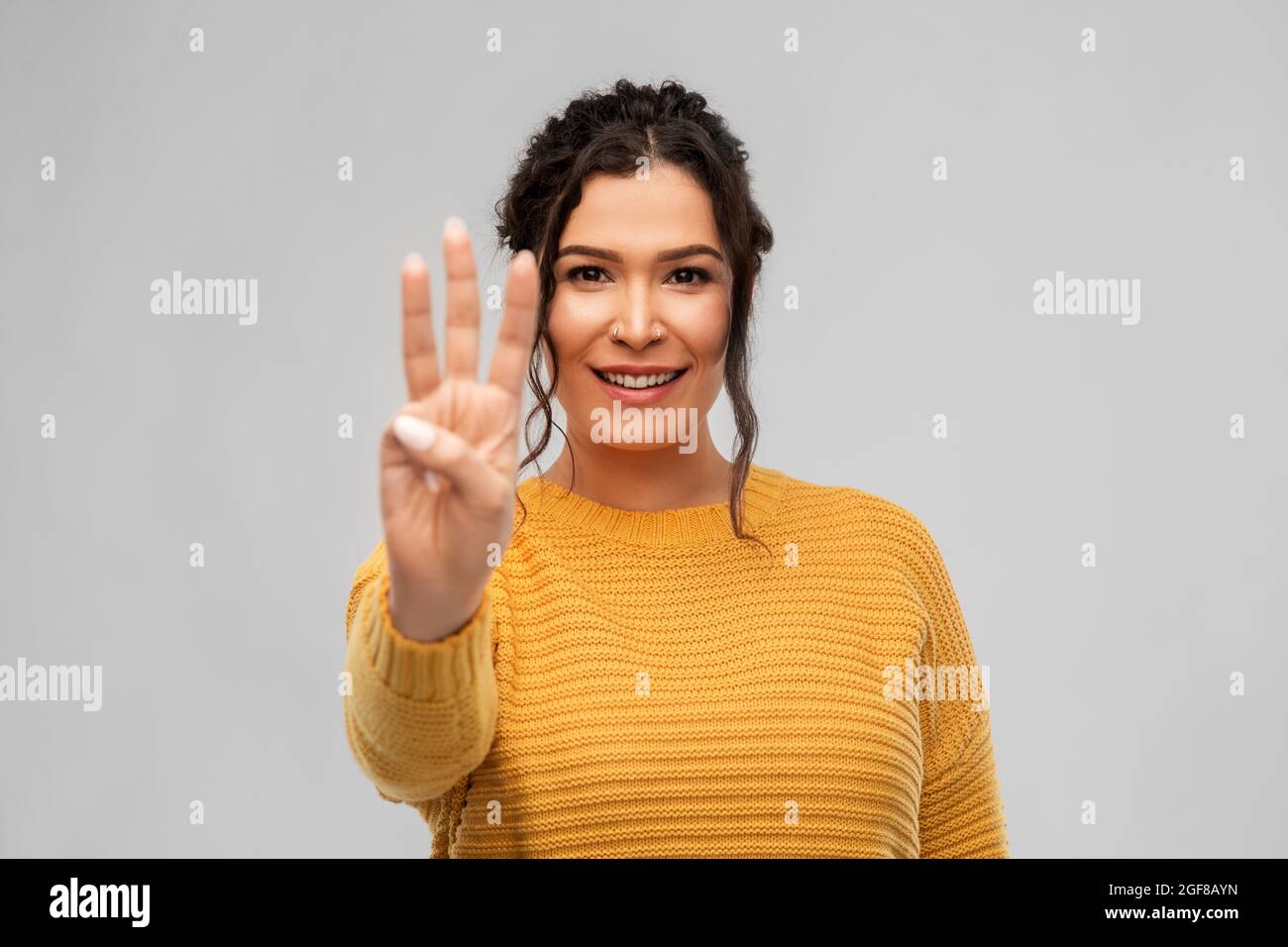 happy woman in pullover showing three fingers Stock Photo