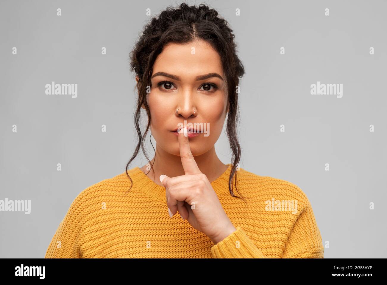 young woman with pierced nose making hush gesture Stock Photo