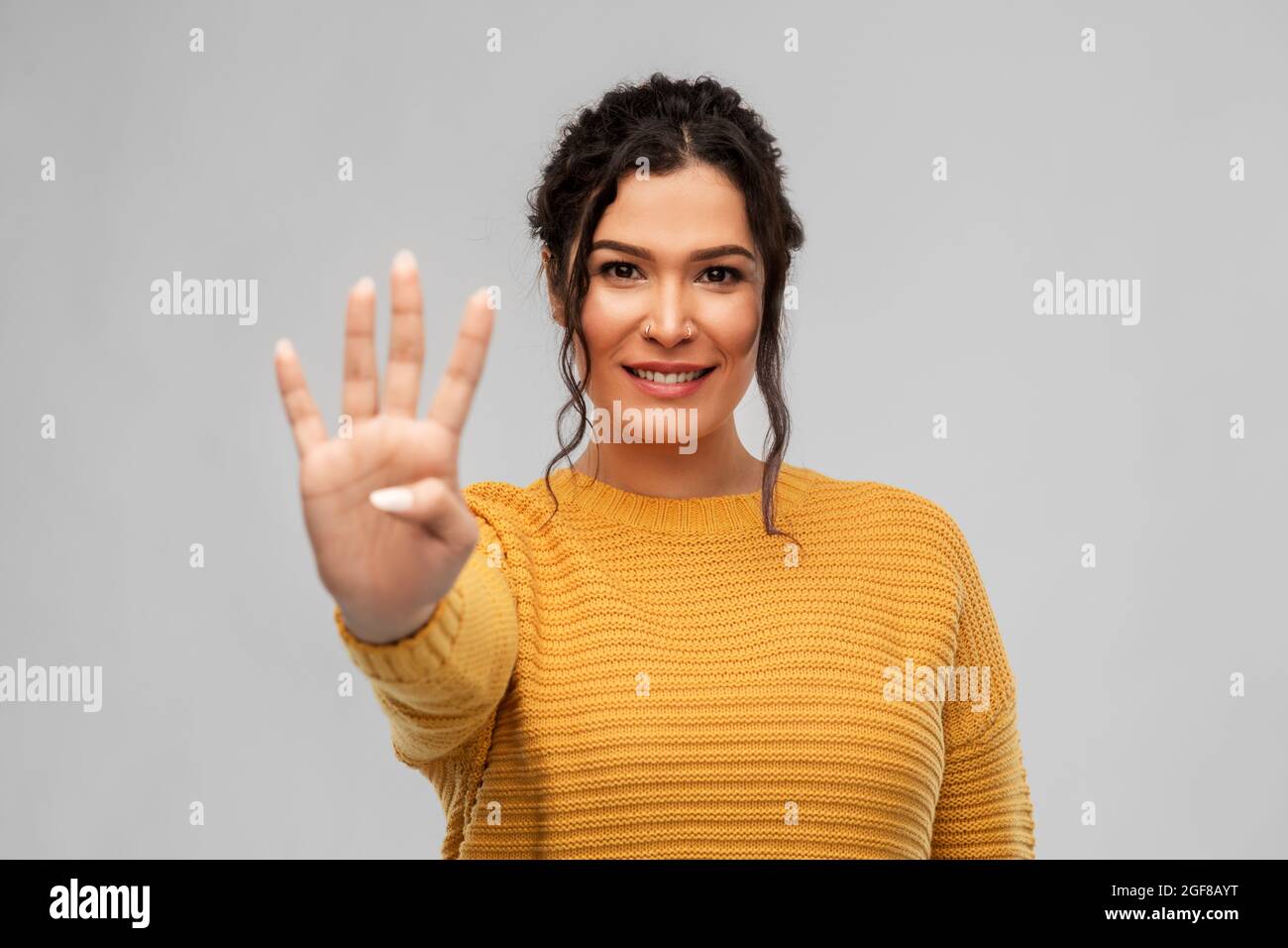 happy woman in pullover showing four fingers Stock Photo