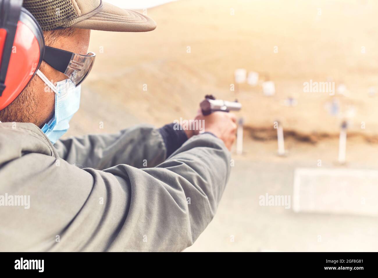 Man with hand gun aiming at shooting range and releasing stress