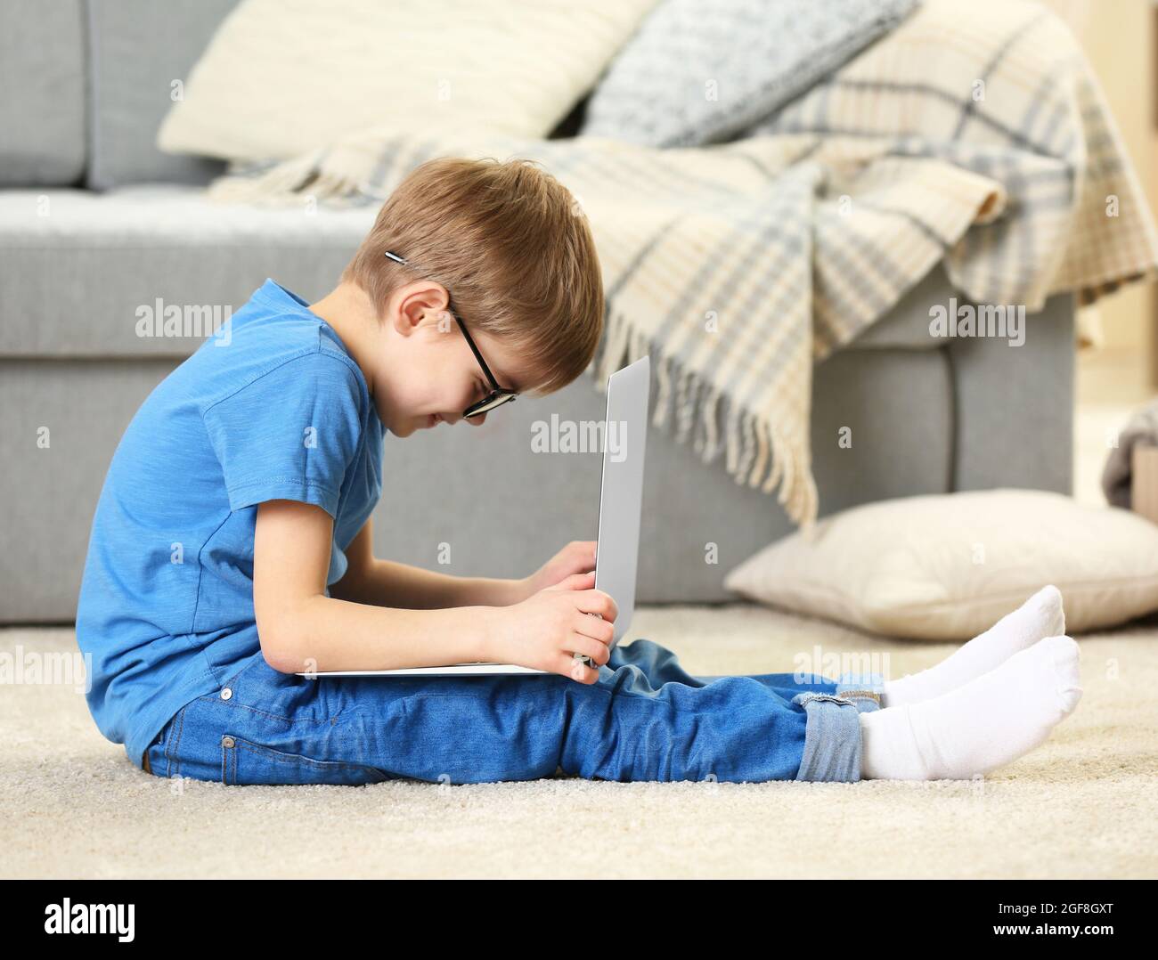 Little boy using laptop on carpet indoors Stock Photo Alamy