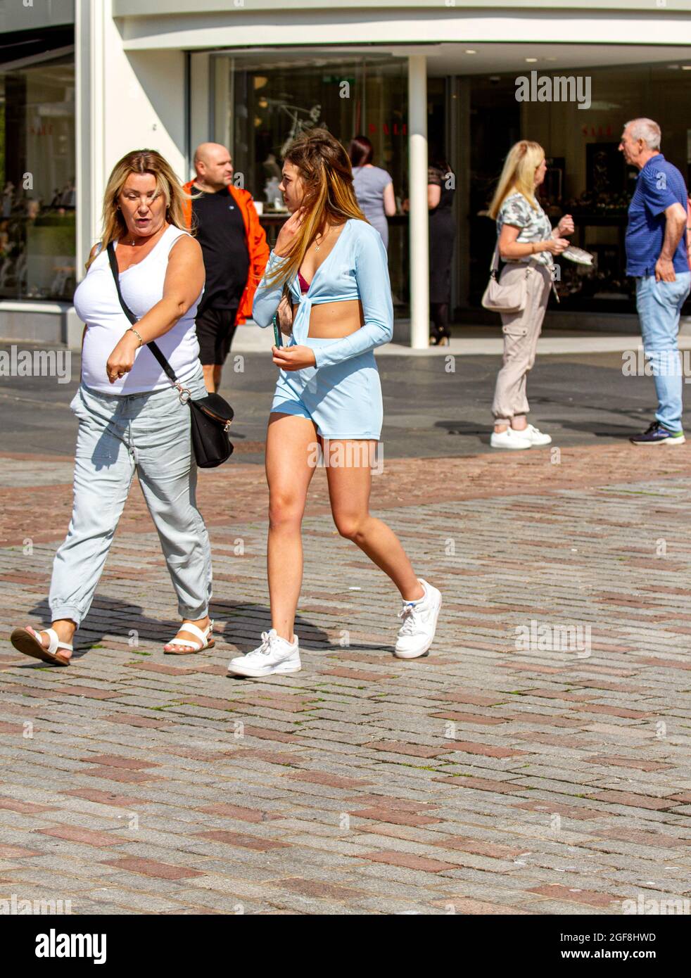 Dundee, Tayside, Scotland, UK. 24th Aug, 2021. UK weather: Glorious warm sunshine across North East Scotland with temperatures reaching 21°C. The late Summer heatwave attracts many local resident to take the day out to enjoy socialising outside after months of Coronavirus lockdowns. A glamorous young woman enjoying the weather walking with her mother whilst having fun in Dundee city centre. Credit: Dundee Photographics/Alamy Live News Stock Photo