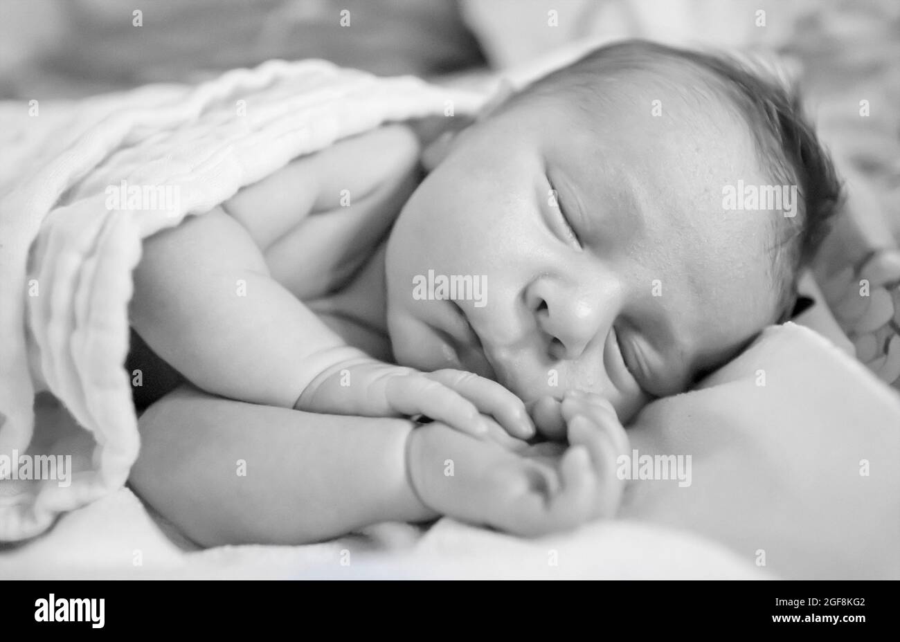 The newborn baby sleeps in the crib. Top view. Happy dreamy face of a